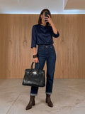 Clueless Paris The Dionne black synthetic handbag with a snakeskin texture held by a woman in a casual outfit.