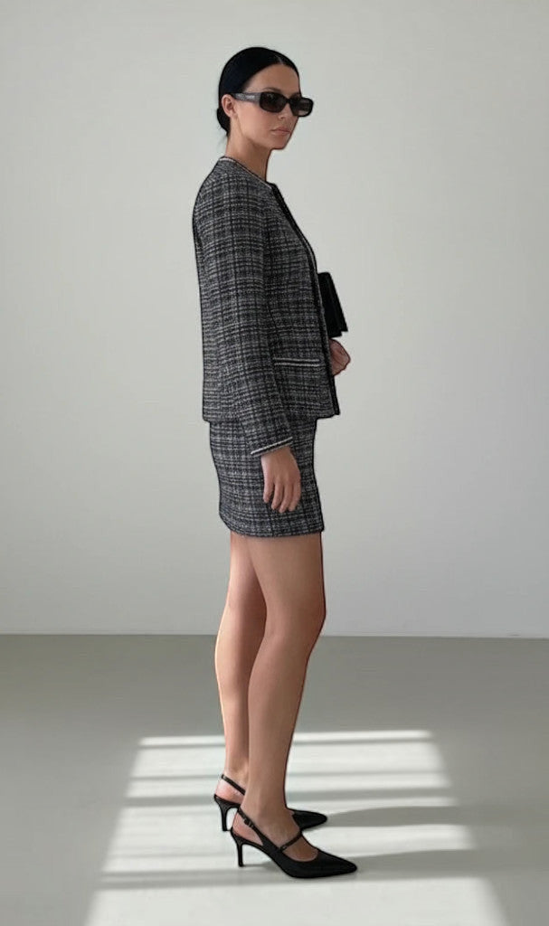 Ensemble Clueless Paris veste et jupe courte en tweed gris et noir, coupe ajustée, porté par une femme avec escarpins