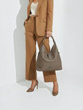 Clueless Paris Georges Rech taupe grained faux leather hobo bag held by a woman in a matching brown suit