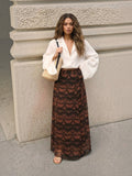 Clueless Paris long wrap skirt in brown and black graphic print with side tie, worn by a model with a white blouse.