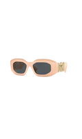 Lunettes de soleil Versace Biggie rose pâle avec monture oversized et médaillon doré emblématique chez Clueless Paris