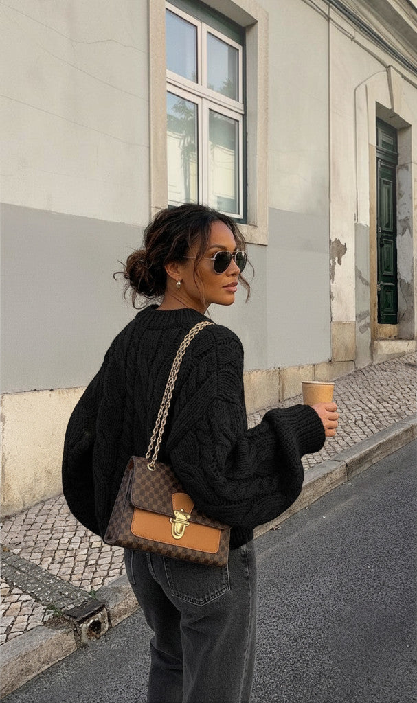 Femme portant un pull Clueless Paris noir en maille torsadée oversize avec un sac à main à bandoulière dans la rue