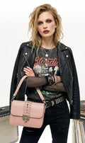 Modèle portant un sac à bandoulière rose poudré Clueless Paris avec clous métalliques et veste en cuir rock