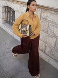 Clueless Paris elegant handbag with rigid handle and snakeskin pattern held by a woman in a mustard shirt